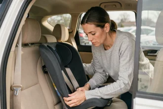 Mère vérifiant un réhausseur auto dans le siège arrière d'un SUV familial